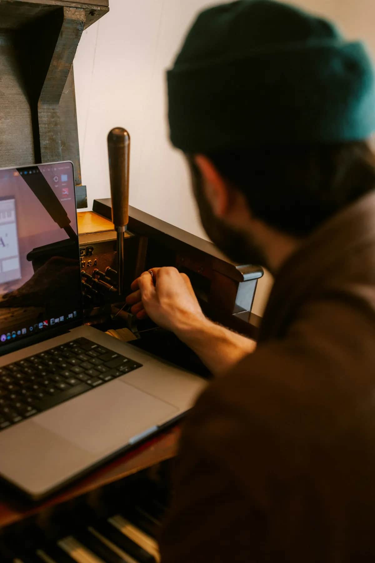 Muž používá notebook u tradičního tiskařského stroje