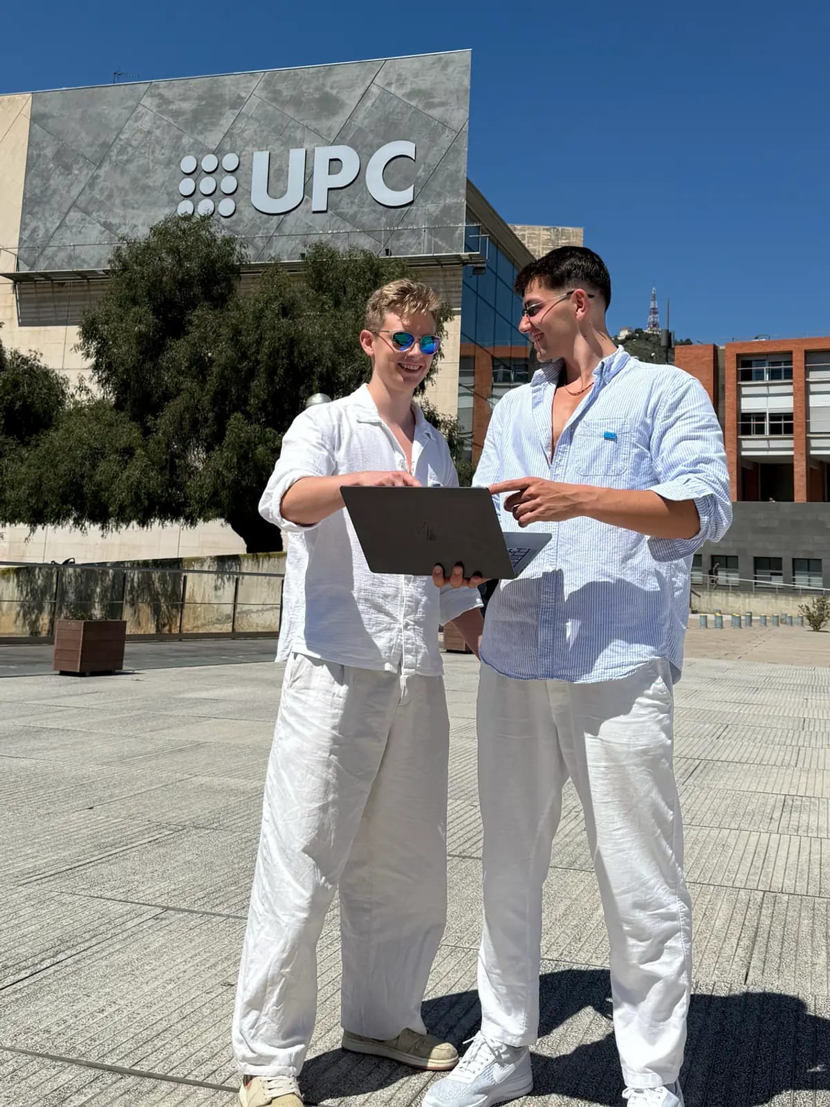 Dva lidé u otevřeného notebooku před budovou univerzitního kampusu v Barceloně.