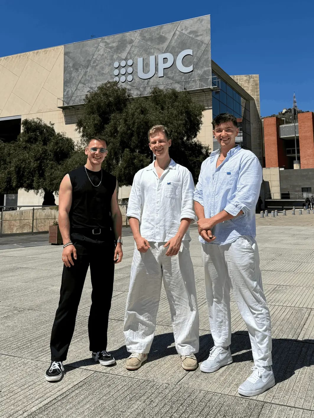 Tři lidé stojí před budovou univerzitního kampusu v Barceloně.