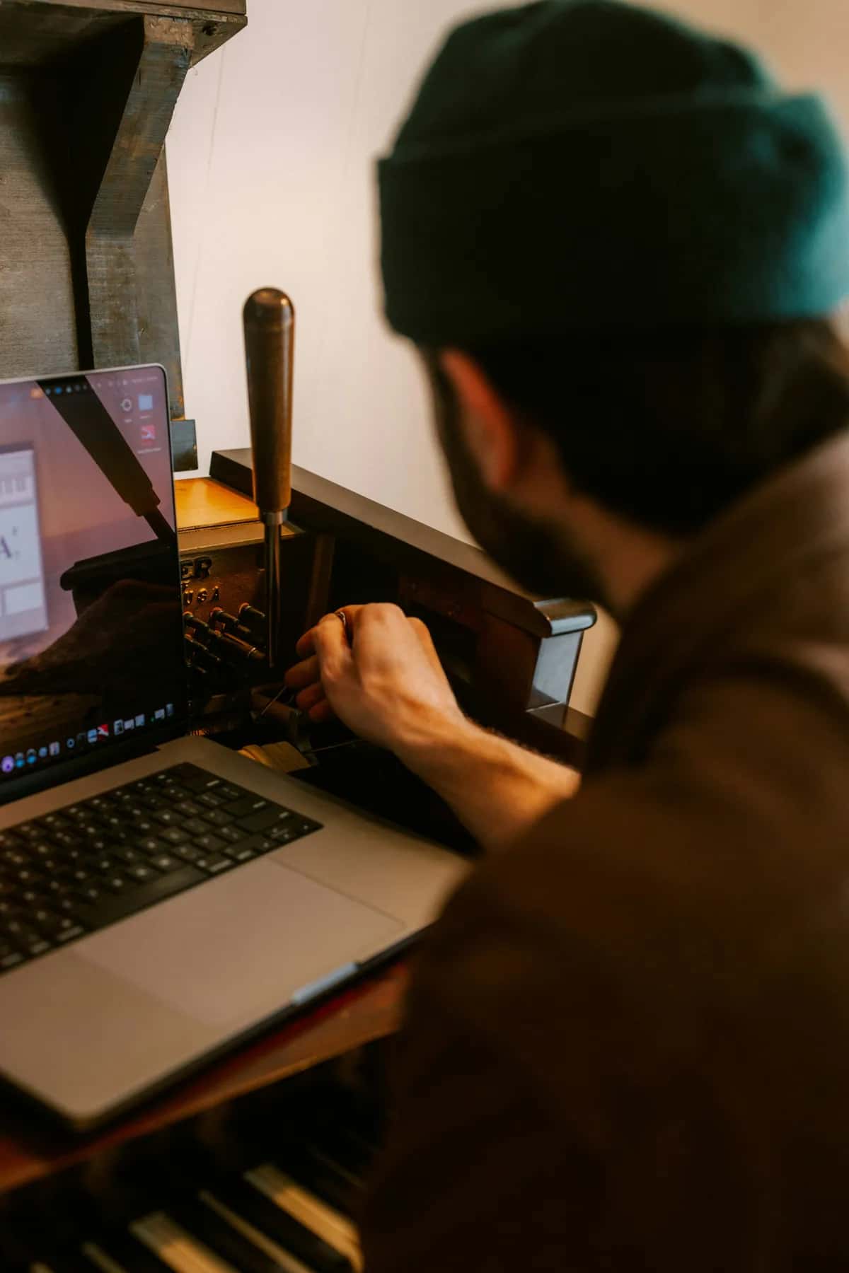Muž používá notebook u tradičního tiskařského stroje