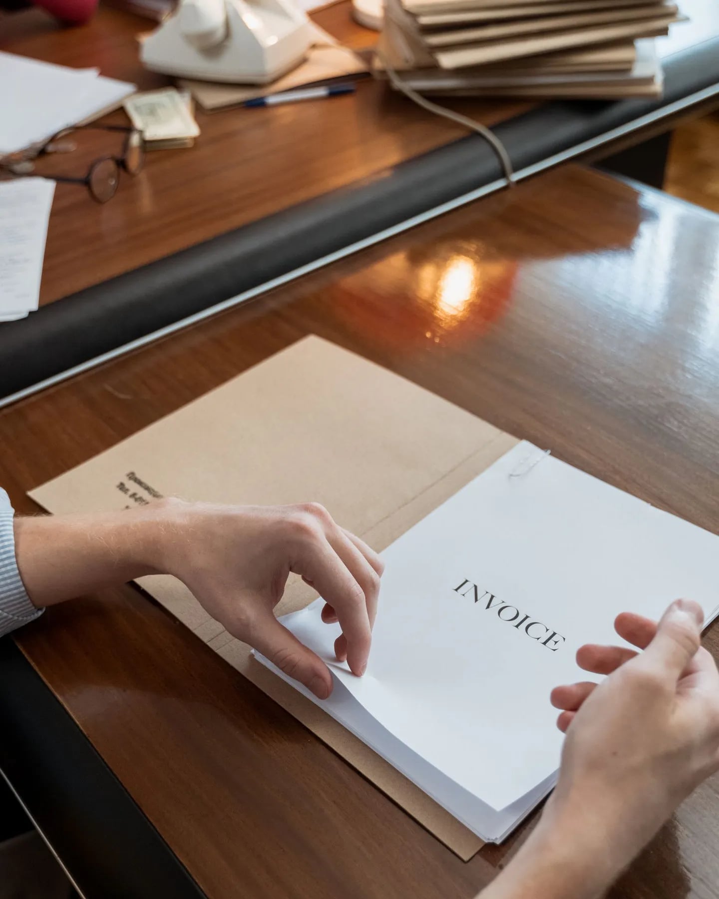 Hands sorting paper invoices on an office desk